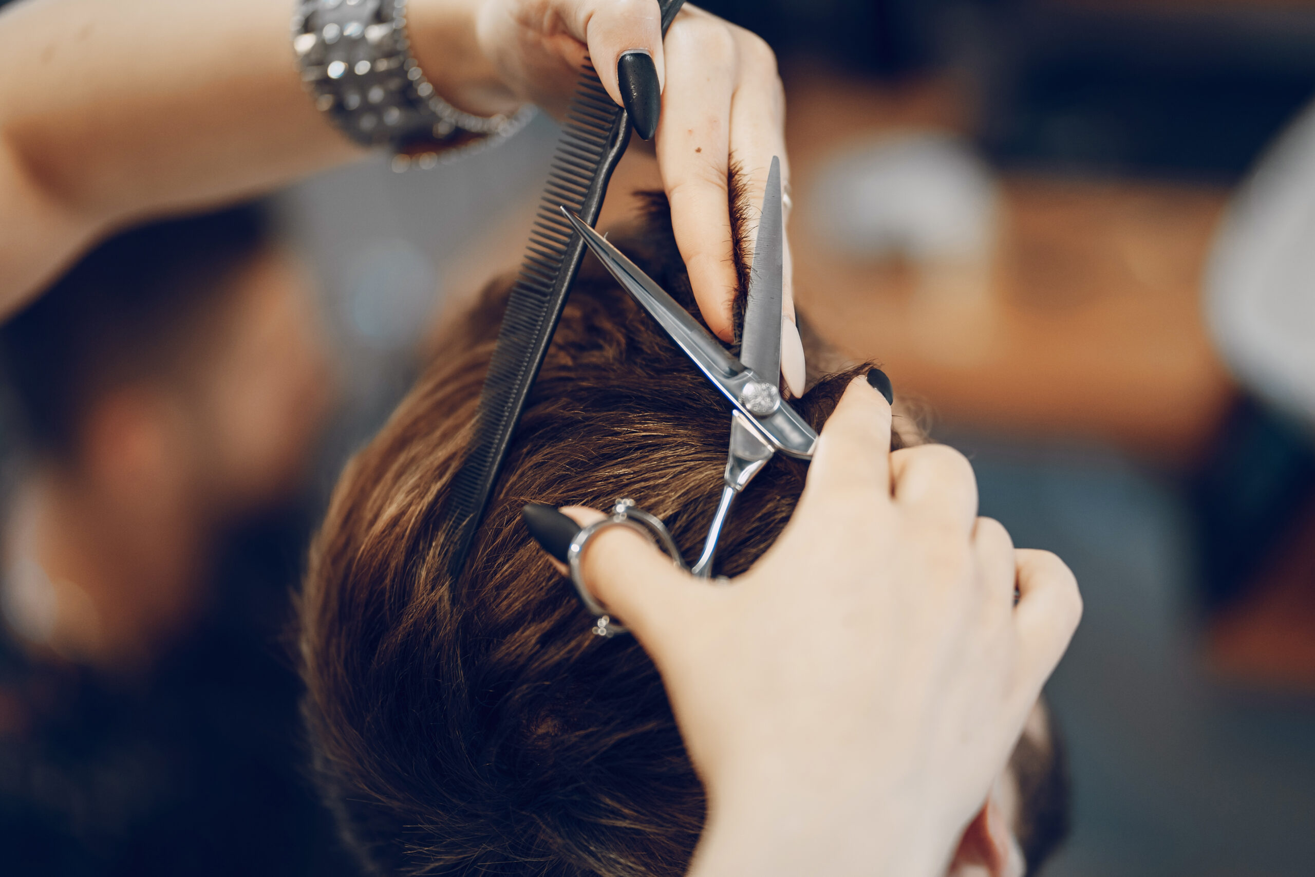 handsome young bearded guy sitting in an armchair in a beauty salon and the girl near him cuts his hair
