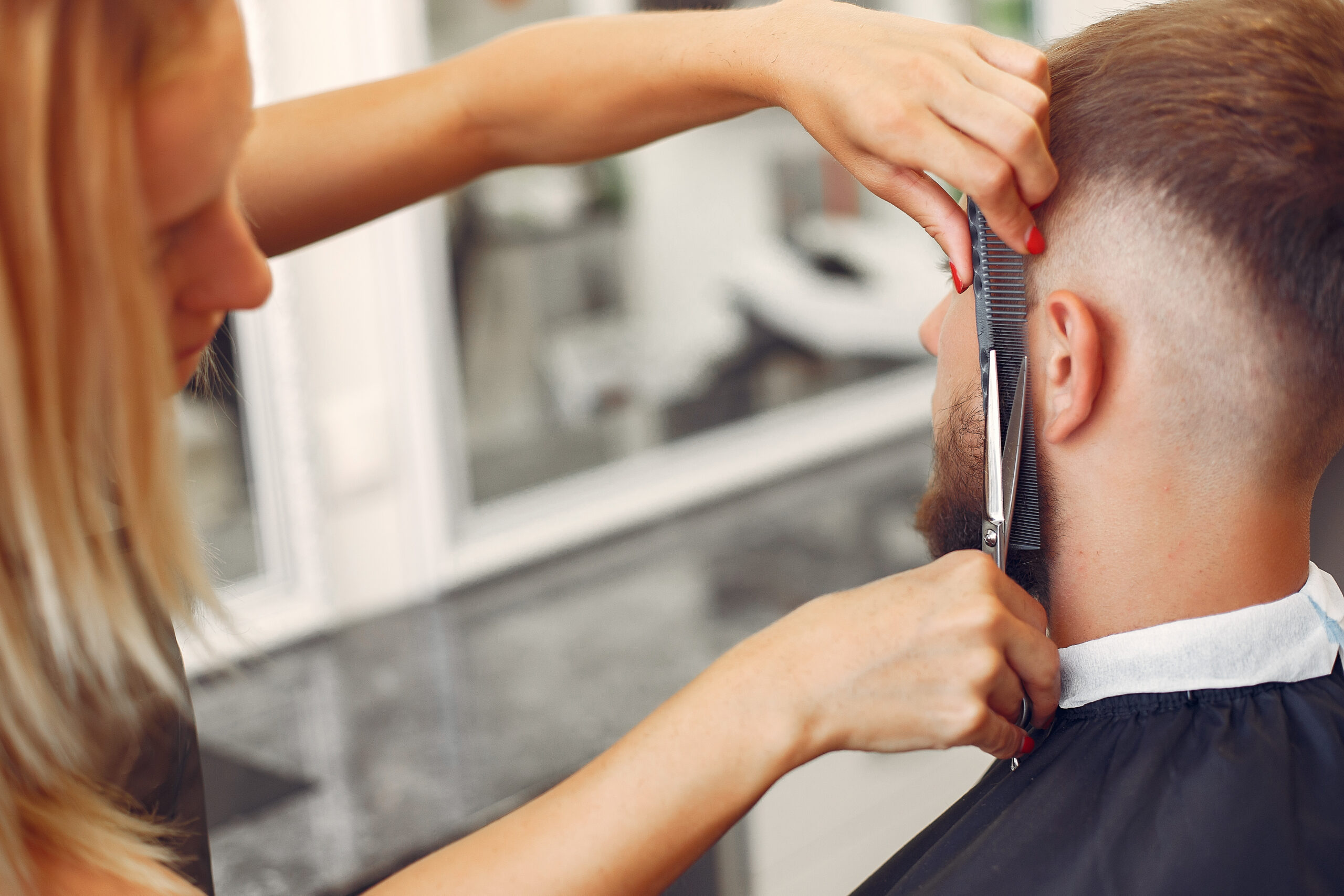 Man with a beard. Hairdresser with a client. Woman with scissors and a comb